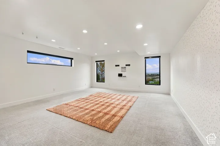 Bright, open room featuring recessed ceiling lighting, expansive windows framed with contemporary trim, neutral wall finishes, and polished concrete flooring throughout
