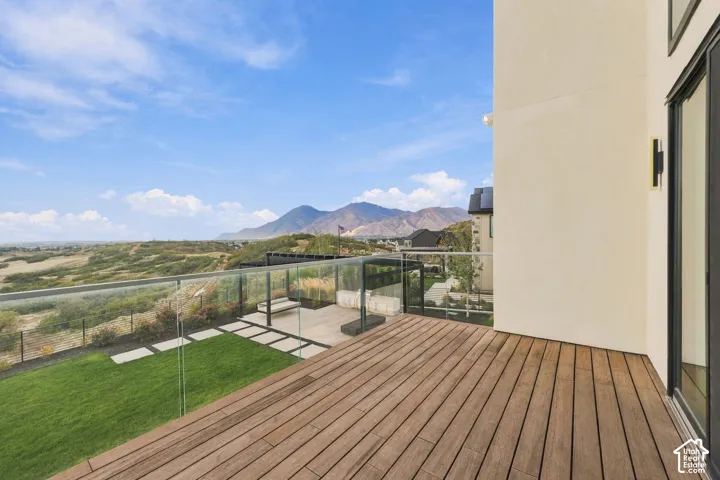 Elevated deck featuring wood-finish decking, glass panel railings, and mountain scenery