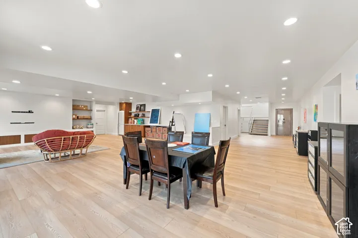 Open-concept living space featuring wood-finish flooring, recessed lighting, and built-in shelving with wooden accents