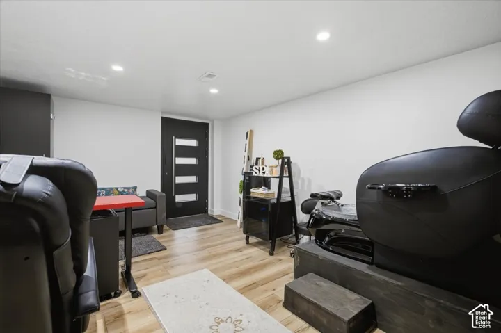 Modern entrance featuring wood-finish flooring, recessed lighting, and a contemporary black entry door with horizontal glass panels