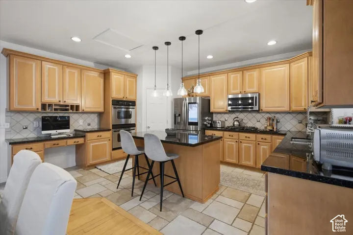 Kitchen featuring light-finish cabinetry, dark stone countertops, tile backsplash, built-in double wall oven, and a central island with pendant lighting