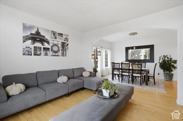 Open-concept living space featuring wood-finish flooring, a prominent architectural archway, and multi-pendant lighting