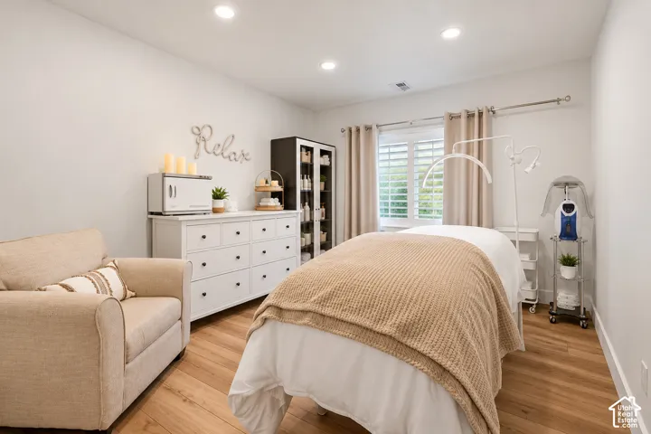 Room featuring wood-finish flooring, recessed lighting, and a plantation shutter window treatment