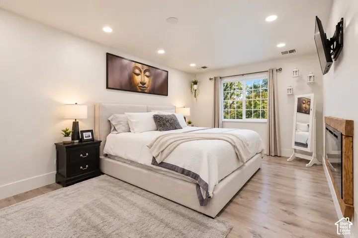 Wood-finish flooring, recessed lighting, and a wall-mounted fireplace with a wooden surround