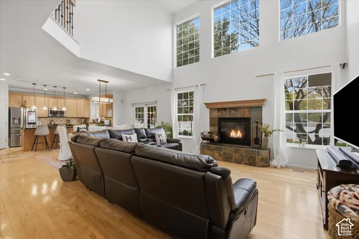 Double-height ceiling, fireplace with stone surround, wood-finish flooring, multi-pane windows, and recessed lighting