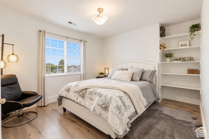 Wood-finish flooring, built-in shelving unit, multi-pane window, and decorative ceiling fixture