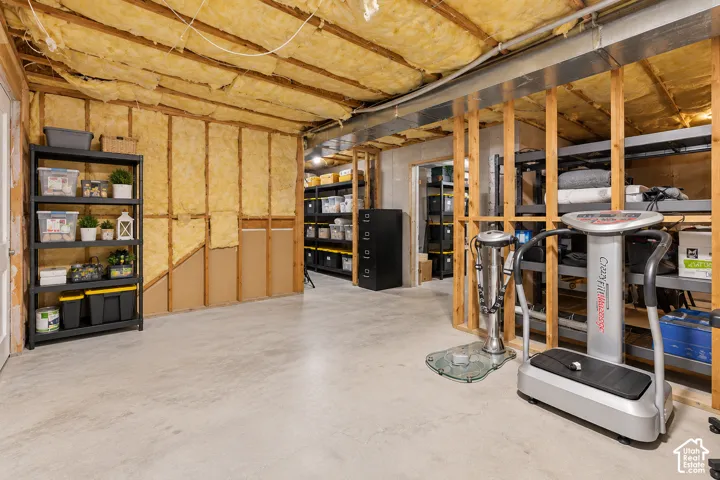Unfinished basement featuring concrete flooring, exposed wood stud framing, and fiberglass batt insulation
