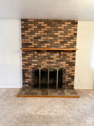 Floor-to-ceiling multi-tonal brick fireplace featuring a wood mantel and a brick hearth