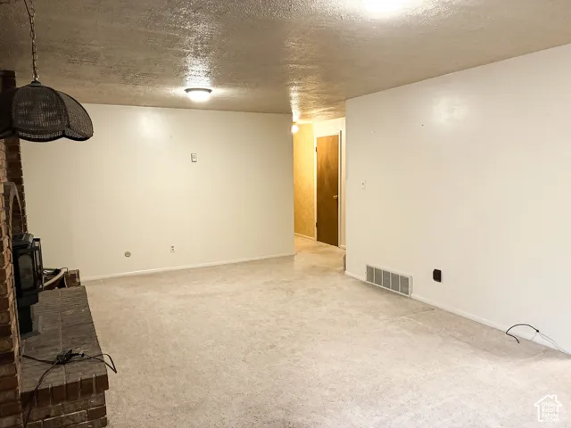Brick fireplace with a raised masonry hearth, carpeted flooring, and neutral wall finishes