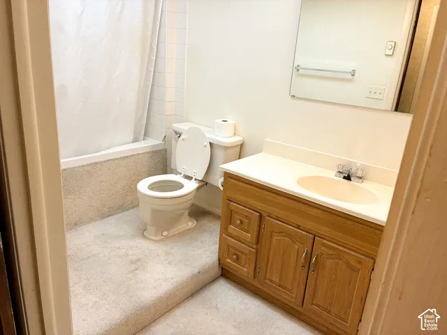 Bathroom featuring a wood-finish vanity with an integrated basin, a wall-mounted mirror, and a bathtub with a tiled surround