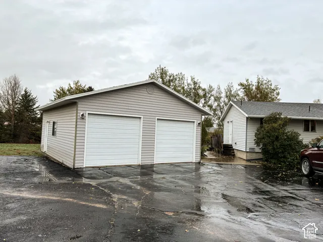 Detached two-car garage featuring light-toned horizontal siding, a gabled roofline, and two overhead garage doors