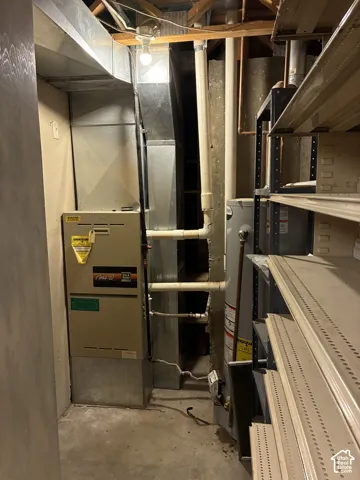 Utility area featuring a forced-air furnace, vertical metal ductwork, and a water heater