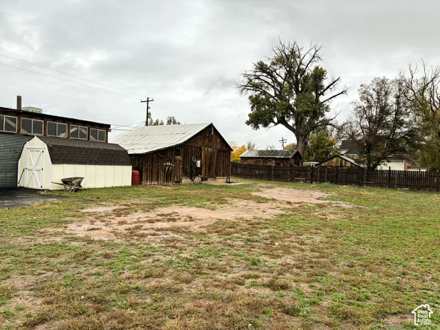 Expansive lot featuring multiple outbuildings, wood-sided barn, storage structure, and perimeter fencing