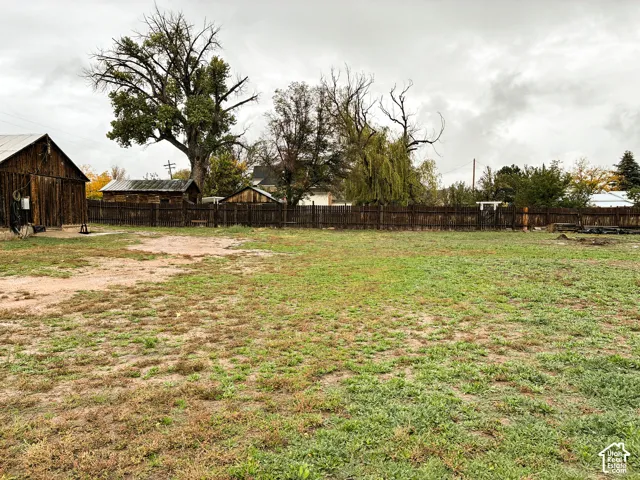 Expansive grounds featuring a wood-plank perimeter fence, mature trees, and rustic outbuildings