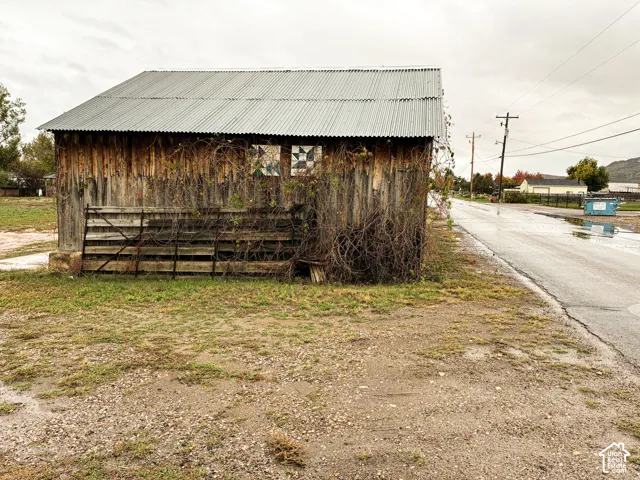 Rustic wood-sided outbuilding featuring a corrugated metal roof and decorative exterior panels