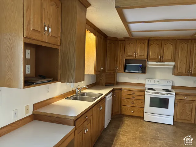 Kitchen featuring wood cabinetry, solid-surface countertops, dual-basin stainless steel sink, built-in microwave, and recessed ceiling lighting