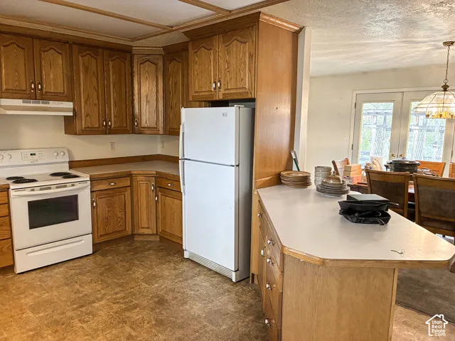 Kitchen featuring wood cabinetry, integrated peninsula, white appliances, and resilient vinyl flooring