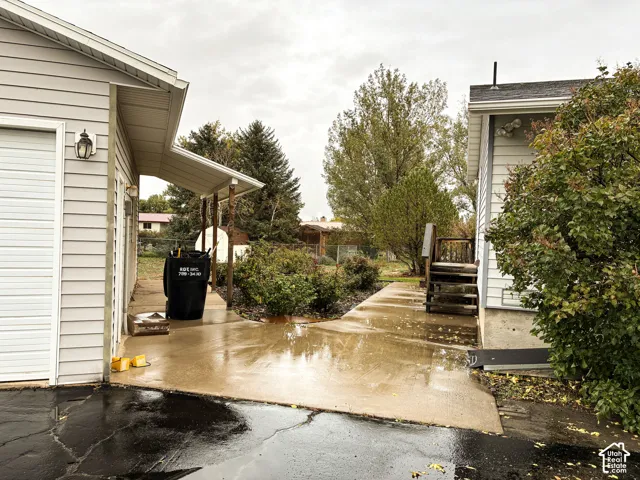 Concrete driveway, horizontal siding, covered exterior walkway, and mature landscaping