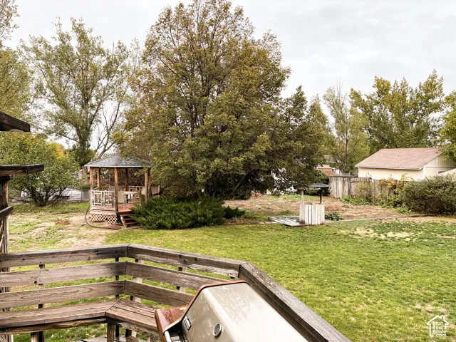 Backyard featuring an elevated wood deck, a covered gazebo with lattice detailing, and mature trees