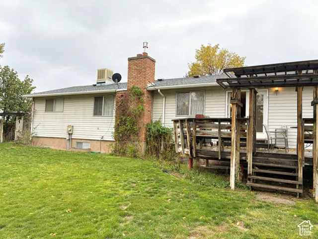 Deck featuring horizontal siding, a central brick chimney, a wood-frame deck, and an attached timber pergola