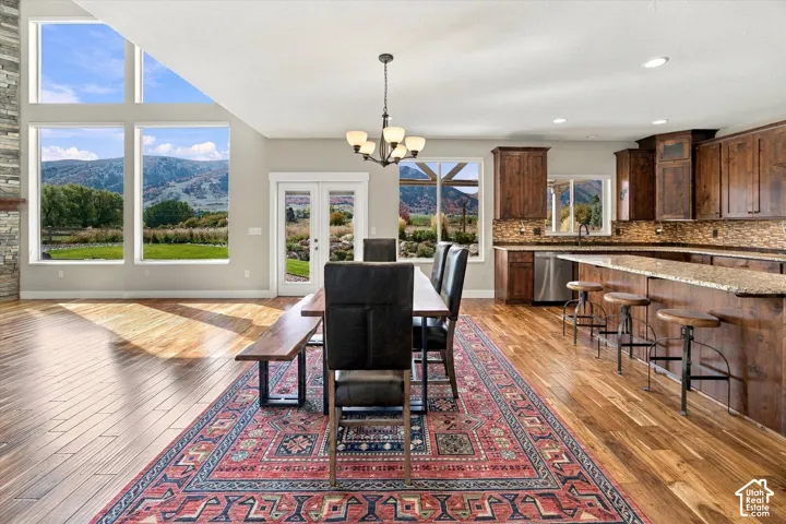 Open-concept space featuring floor-to-ceiling windows with mountain scenery, wood-finish flooring, dark wood cabinetry, a stone-tile backsplash, and a multi-tiered stone accent wall