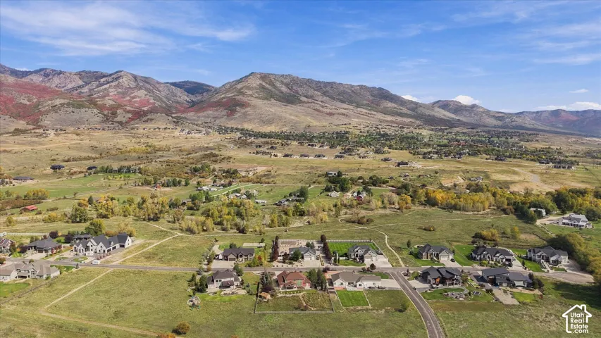Aerial perspective of an expansive residential lot featuring established paved roads and an expansive mountain range backdrop