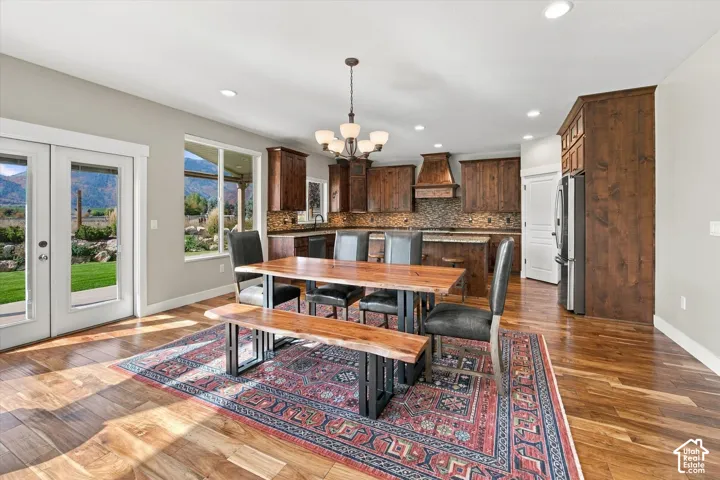 Kitchen featuring wood cabinetry, a decorative wood range hood, recessed lighting, and wood-finish flooring, with glass patio doors revealing mountain scenery