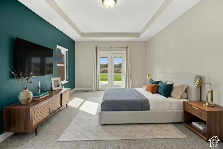 Tray ceiling, accent wall, and glass-paned double doors leading to a patio