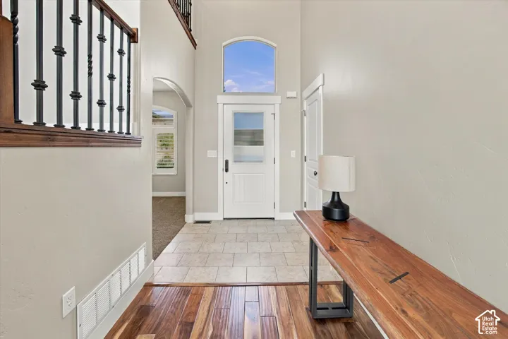 Foyer featuring a high ceiling, arched transom window, tile flooring, and a staircase with metal balusters