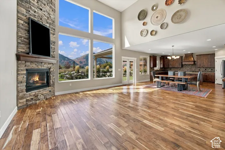 Floor-to-ceiling stone fireplace, soaring windows with mountain scenery, wood-finish flooring, and cabinetry with integrated range hood