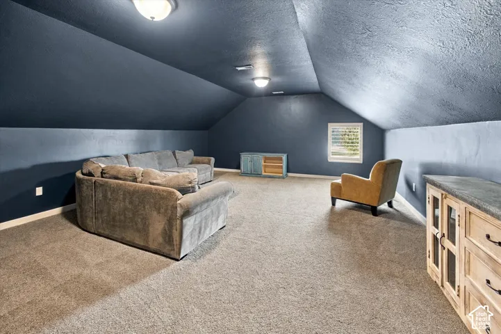 Expansive interior space featuring vaulted ceilings, neutral carpeting, recessed ceiling lighting, and a window