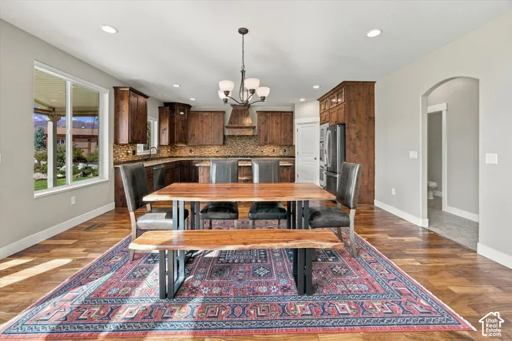 Kitchen featuring custom wood cabinetry, tiled backsplash, built-in stainless steel appliances, wood-finish flooring, and recessed lighting