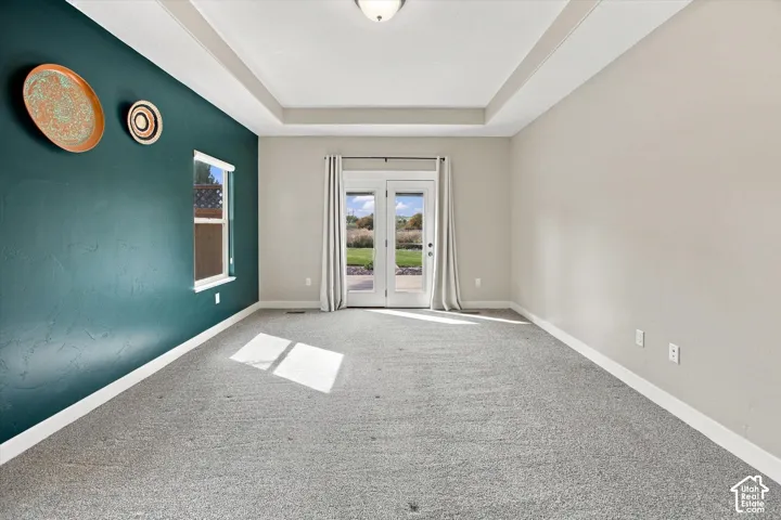 Interior space featuring a recessed tray ceiling, dual French doors with glass panes, and a singular accent wall
