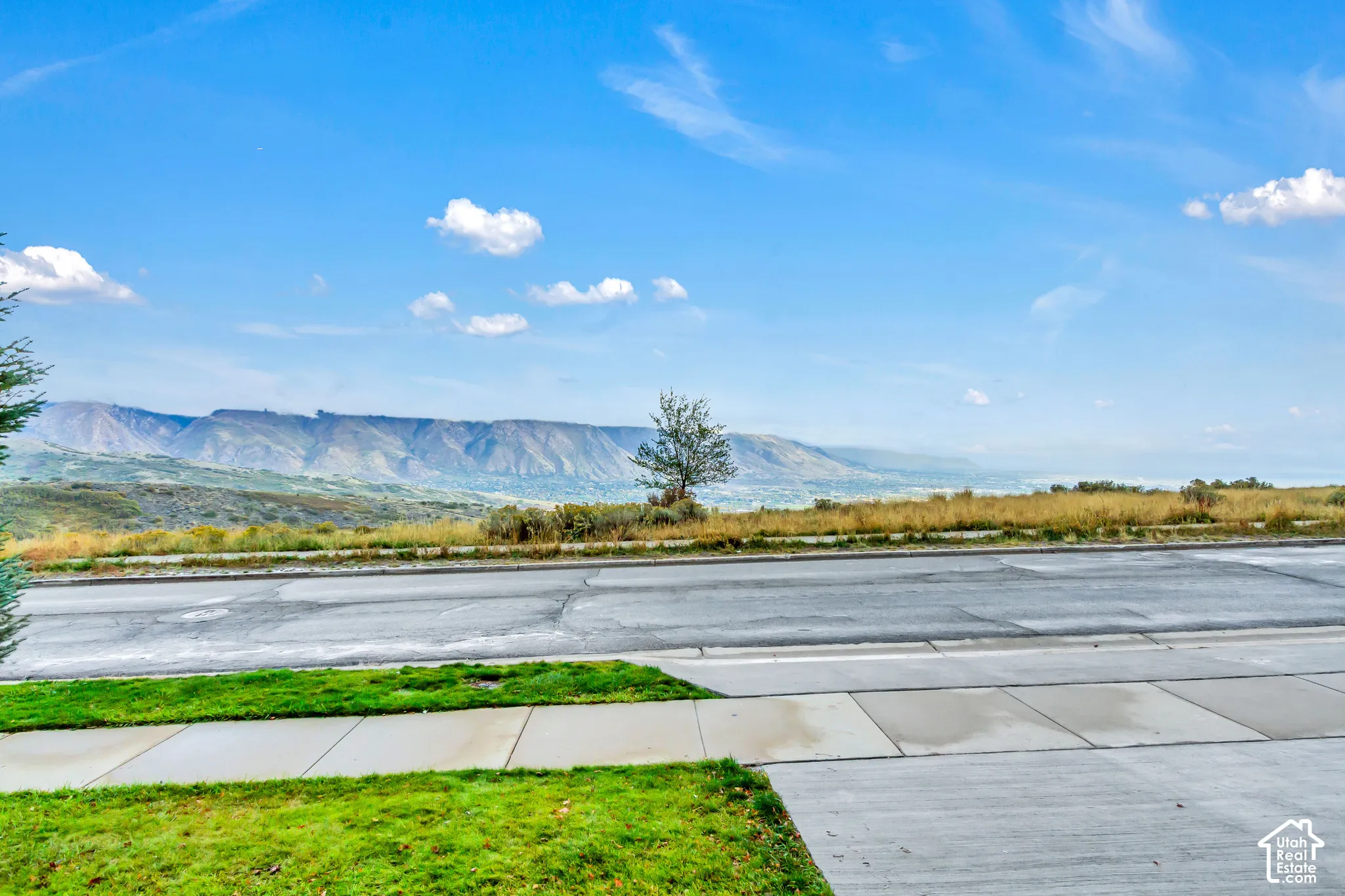 Paved sidewalk and manicured turf grass featuring a mountain backdrop and open landscape