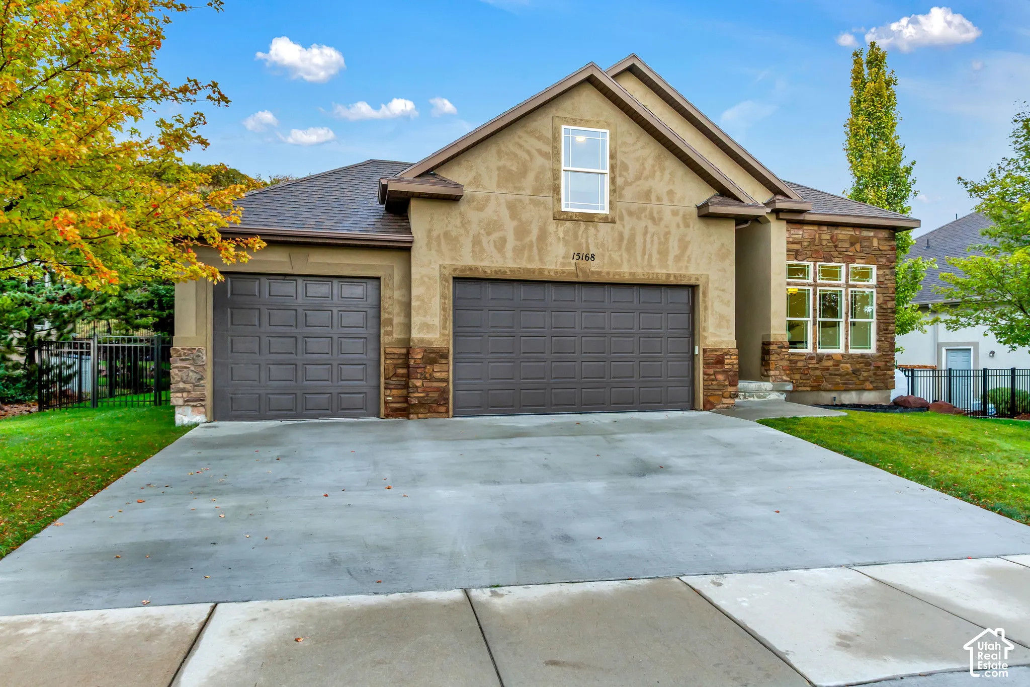 Exterior facade featuring a combination of stucco and stone veneer, a three-car garage, and a concrete driveway
