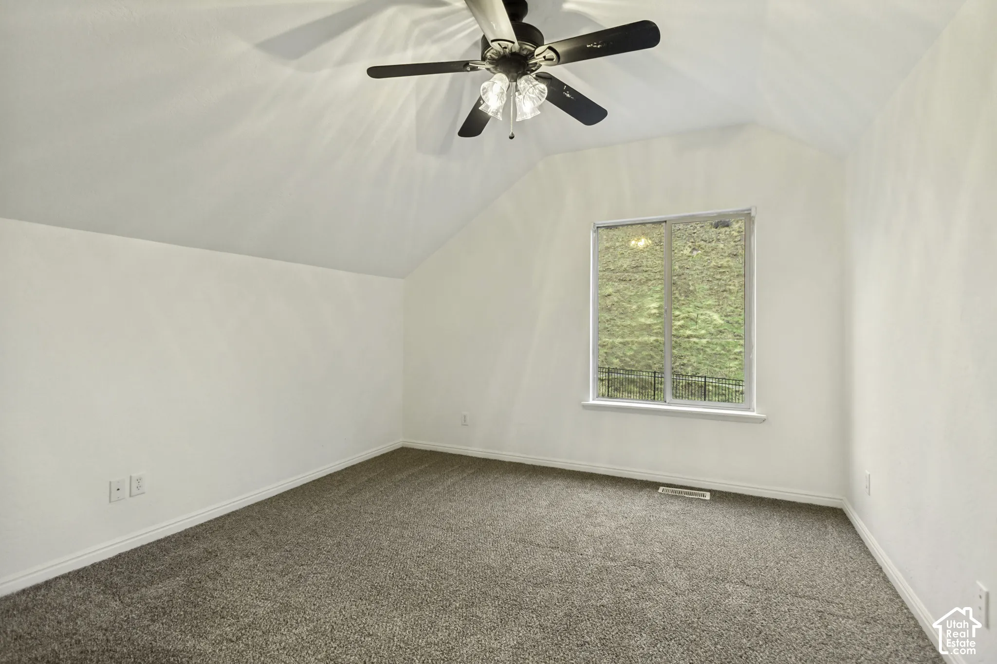 Vaulted ceilings with a multi-blade ceiling fan, wall-to-wall carpeting, and a large sliding window