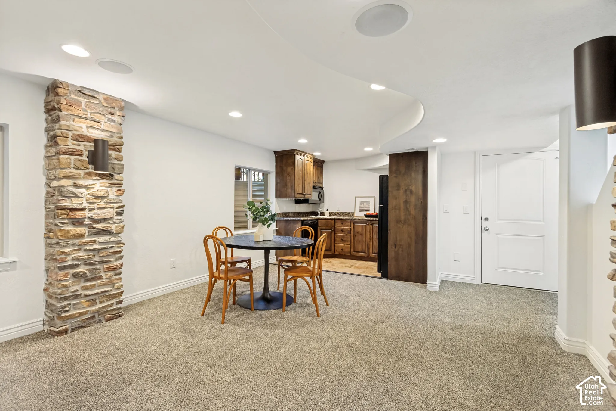 Interior space featuring stacked stone columns, recessed ceiling lighting, wall-mounted light fixtures, built-in cabinetry, and neutral carpeting