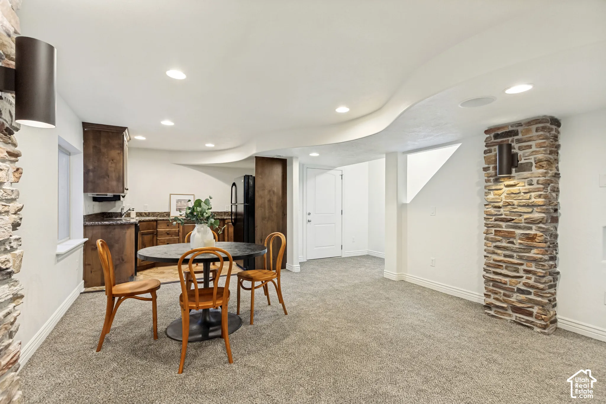 Kitchenette featuring dark wood cabinetry, stone countertops, recessed lighting, and dual floor-to-ceiling stone pillar accents