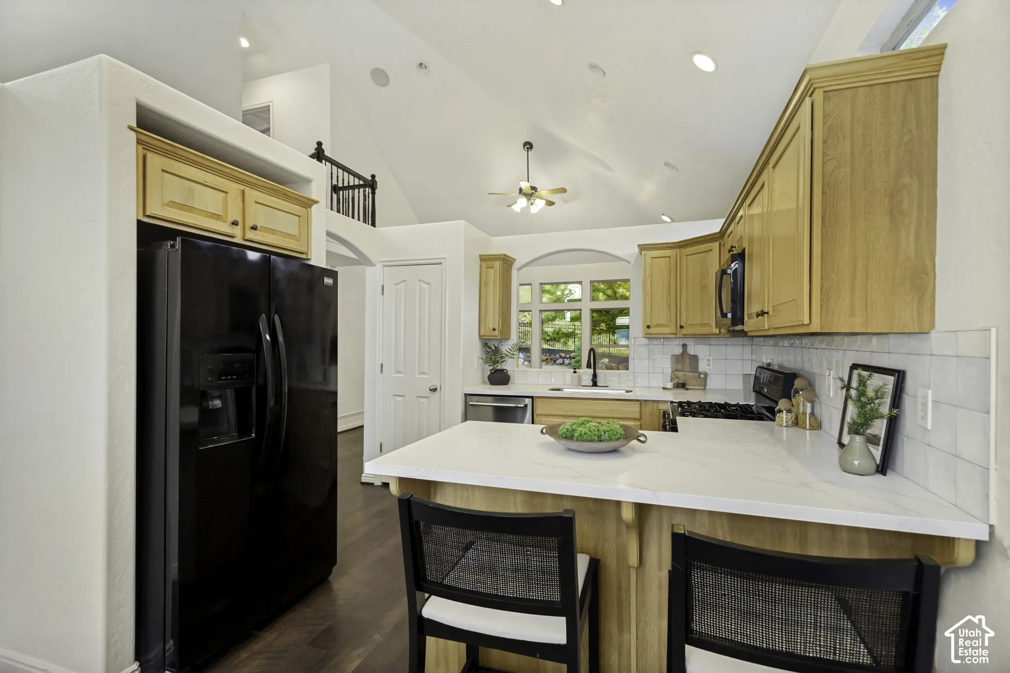 Kitchen featuring vaulted ceilings, light wood cabinetry, quartz countertops, white subway tile backsplash, and dark wood-finish flooring