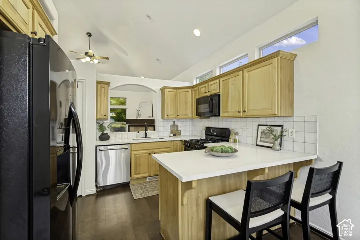 Kitchen featuring shaker-style cabinetry, quartz countertops, a tile backsplash, recessed ceiling lighting, and vaulted ceilings