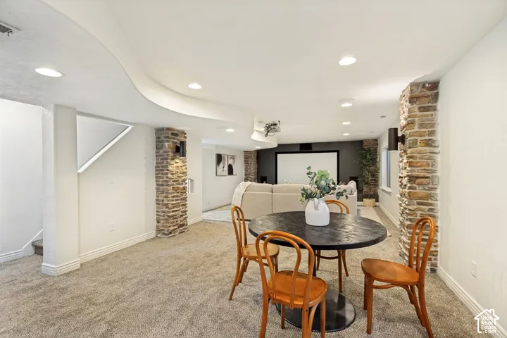 Curved ceiling architectural detail, stacked-stone column accents, recessed lighting, and wall-mounted sconce fixtures