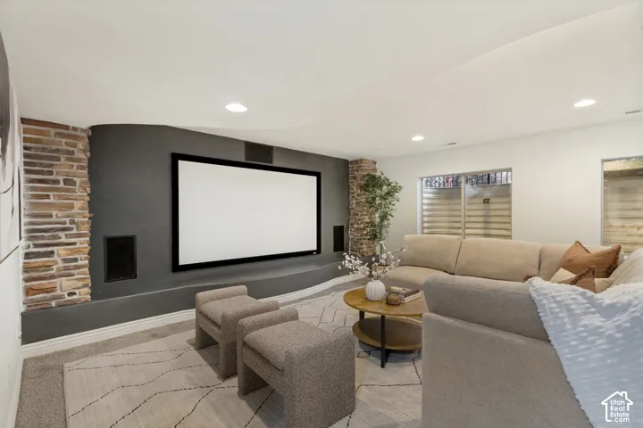 Media room featuring a curved accent wall, built-in display screen, recessed stone columns, integrated speakers, and carpeted flooring