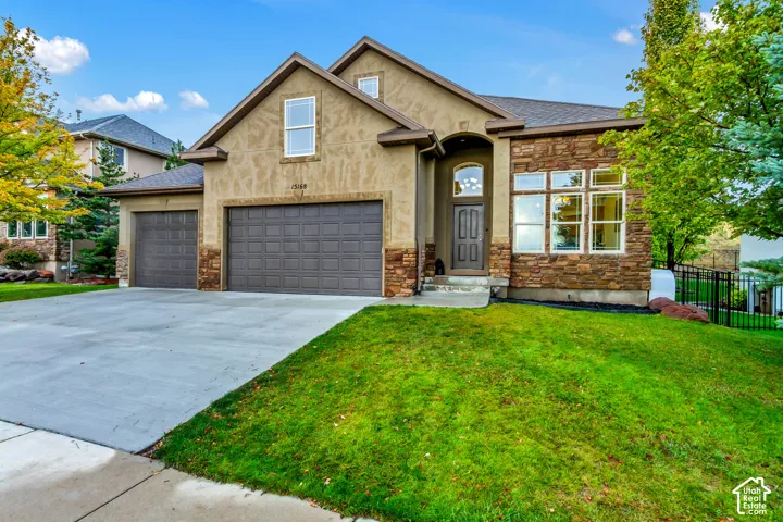 Exterior facade featuring a combination of stucco and natural stone veneer, a multi-gabled roofline, an arched entryway, and a three-car garage