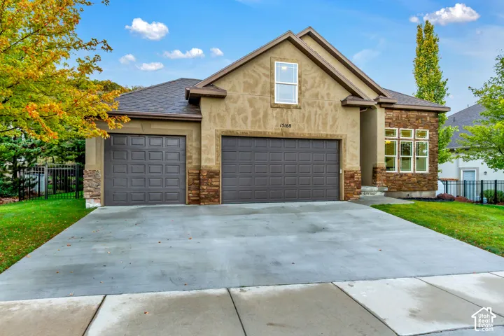 Exterior facade featuring a combination of stucco and stone veneer, a three-car garage, and a concrete driveway