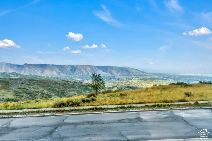 Expansive mountain range backdrop and elevated hillside terrain featuring native grasses and panoramic topography