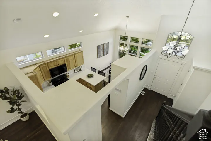 Vaulted ceilings featuring recessed lighting, natural wood-finish cabinetry, a central island with countertop, multi-pane transom windows, and wood-finish flooring