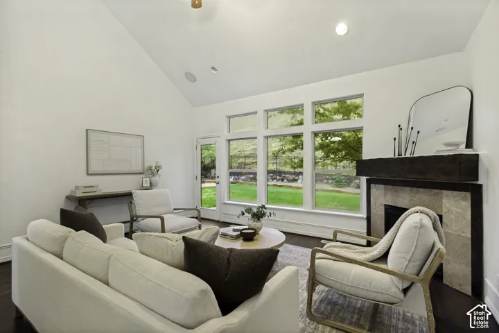Vaulted ceilings, expansive windows, fireplace with stone surround and timber mantel, recessed lighting, and wood-finish flooring