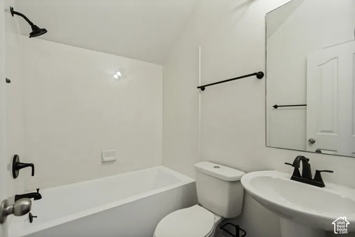 Bathroom featuring a white pedestal sink, porcelain tub, shower head with matte black hardware, and an oversized wall-mounted mirror