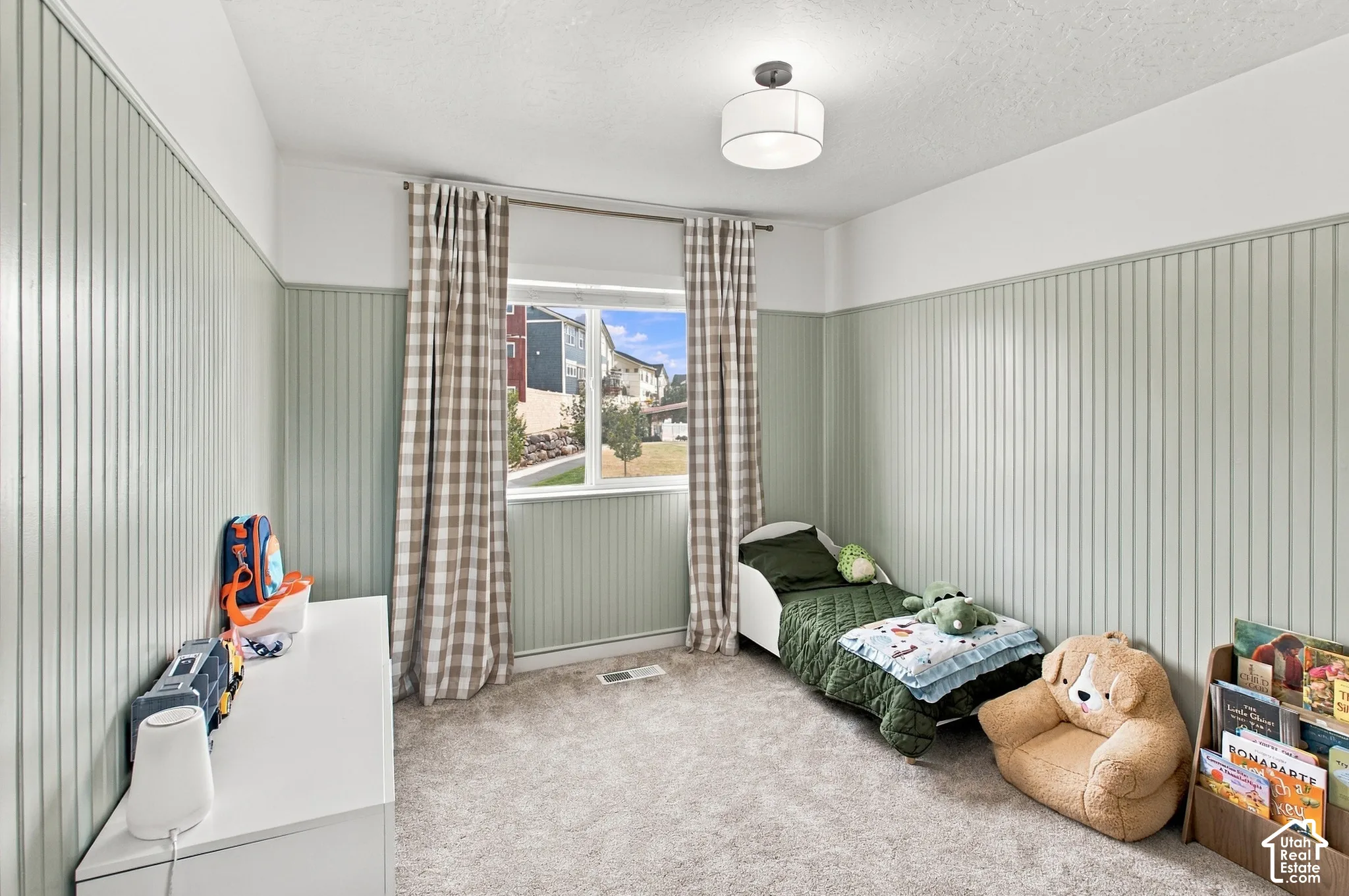 Interior room featuring floor-to-ceiling vertical beadboard wainscoting, neutral carpeting, and a modern drum-style flush-mount light fixture