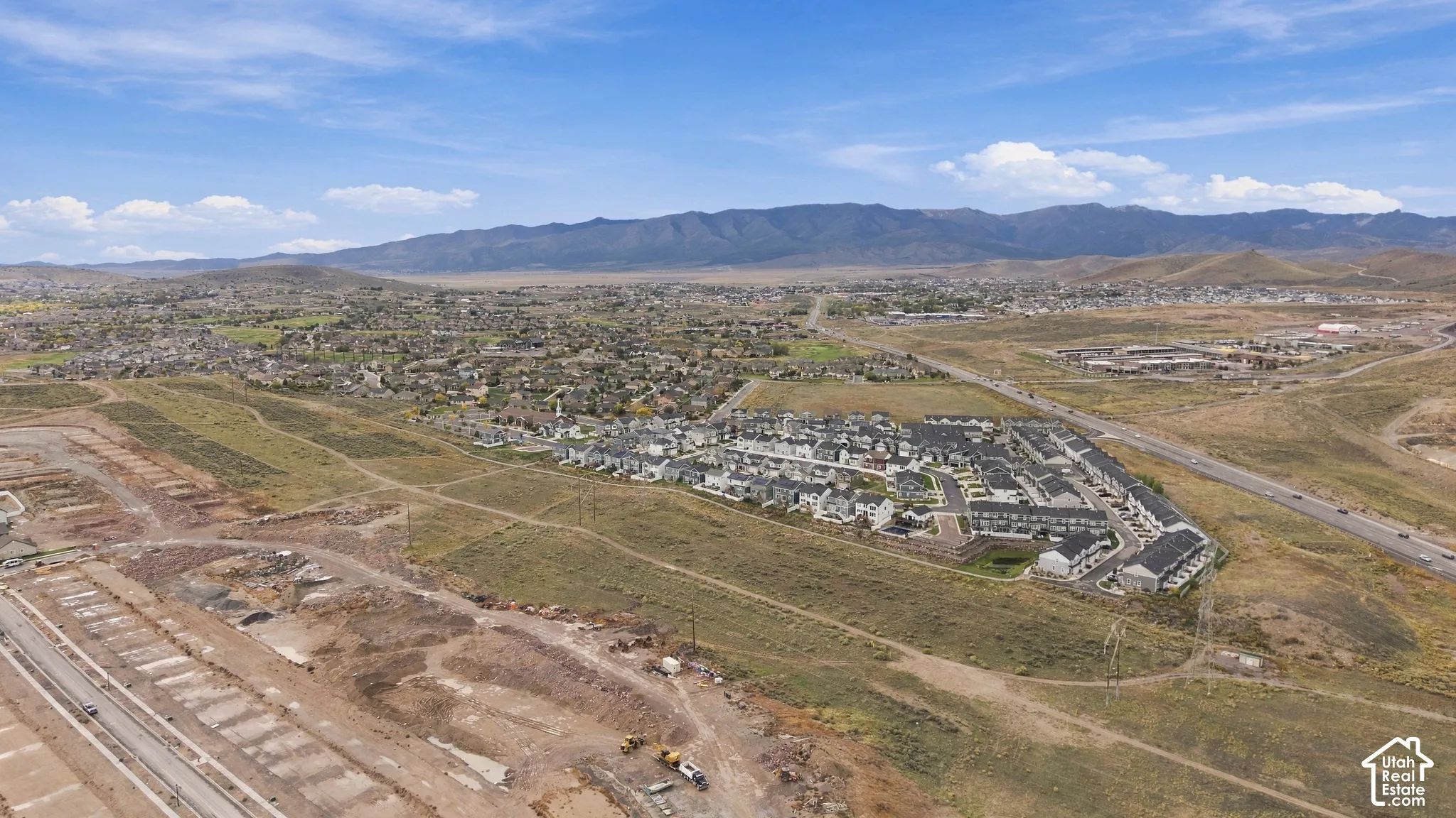 Aerial perspective featuring a residential community situated within a sprawling valley landscape, characterized by prominent mountain range topography and expansive open terrain